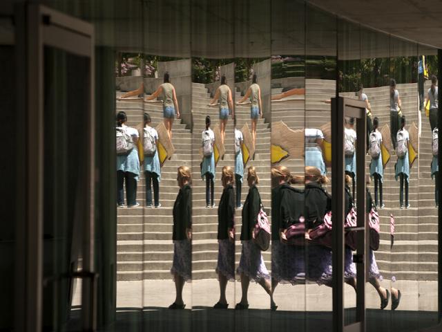 people walking in front of a reflective window